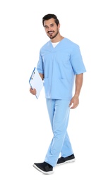 Young male doctor with clipboard walking on white background. Medical service