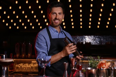 Photo of Bartender with shaker preparing fresh alcoholic cocktail in bar
