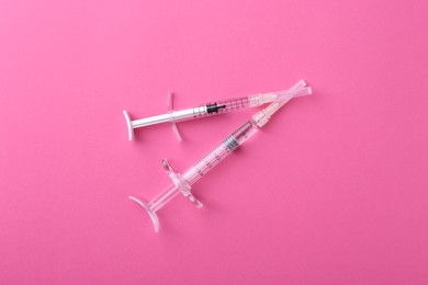 Photo of Injection cosmetology. Two medical syringes on pink background, top view
