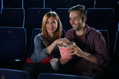 Young couple with popcorn watching movie in cinema theatre