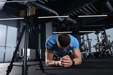 Trainer streaming online workout with phone at gym