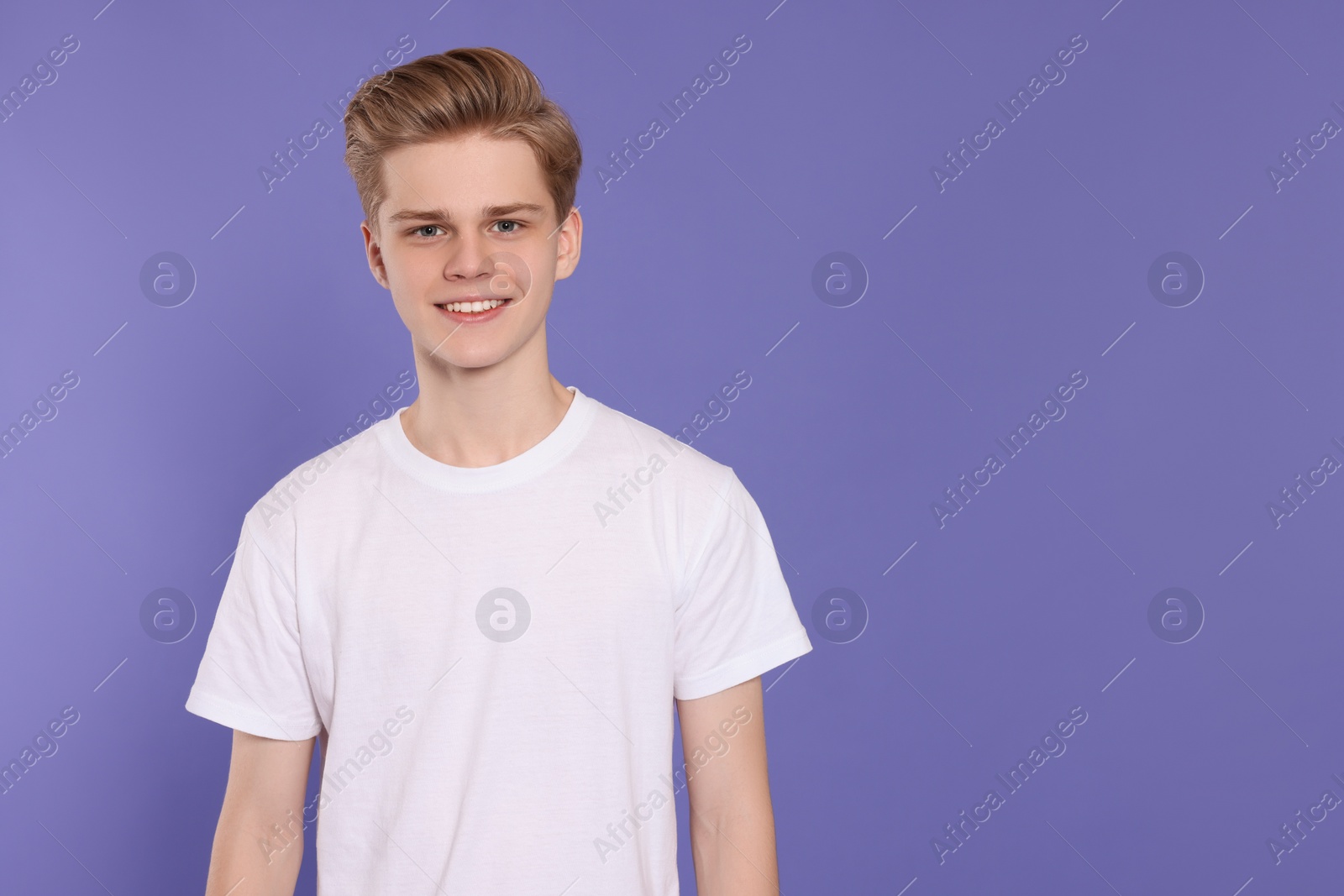 Photo of Portrait of teenage boy on purple background. Space for text