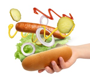 Woman making hot dog on white background, closeup. Ingredients levitating over bun