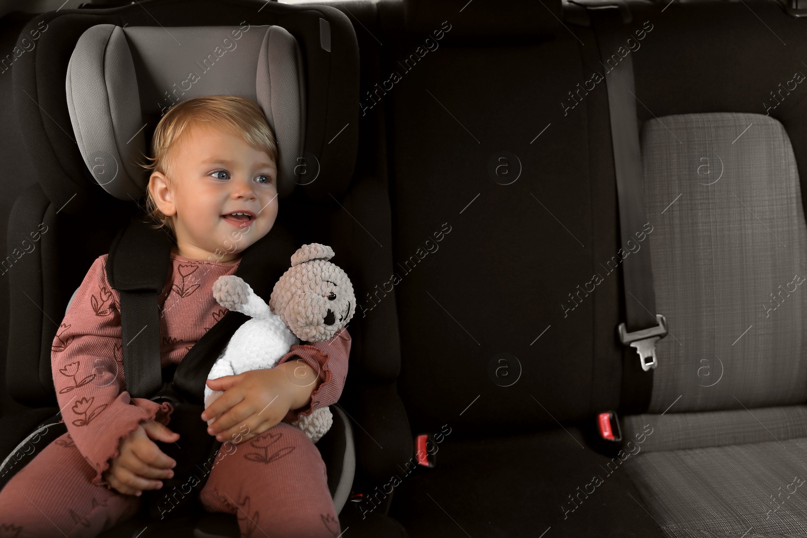 Photo of Cute little girl sitting in child safety seat inside car