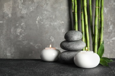 Spa stones with candles and bamboo on table, space for text