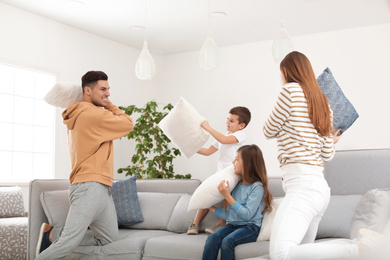 Photo of Happy family having pillow fight in living room