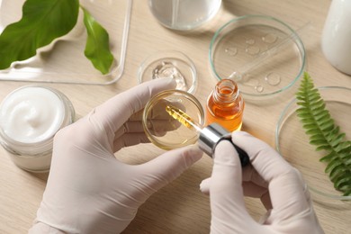 Photo of Scientist making cosmetic product at wooden table, above view