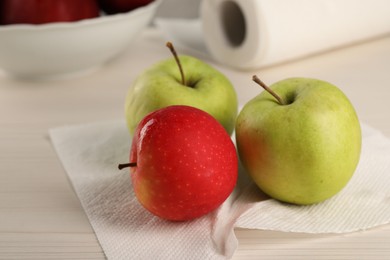 Photo of Fresh apples and paper towel on light wooden table, closeup