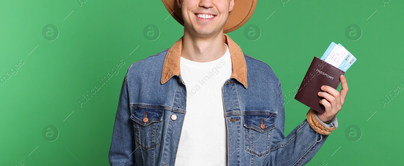 Photo of Smiling man with passport and tickets on green background, closeup