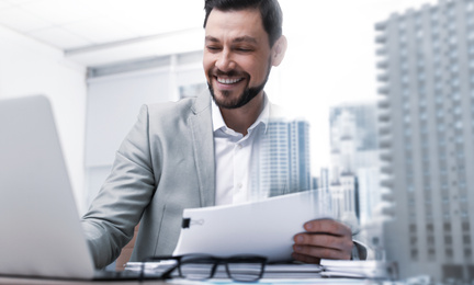 Double exposure of architect working with laptop at table and cityscape