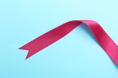 Photo of Simple pink ribbon on color background, top view