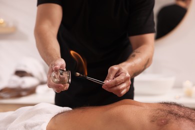 Photo of Therapist giving fire cupping treatment to patient indoors, closeup