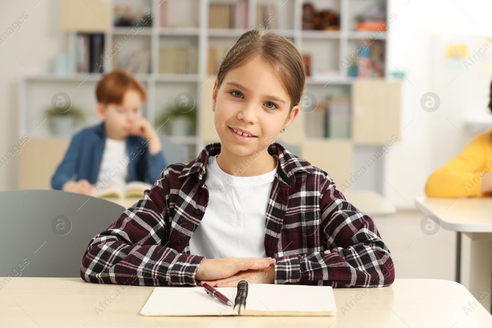 Photo of Smiling little girl studying in classroom at school