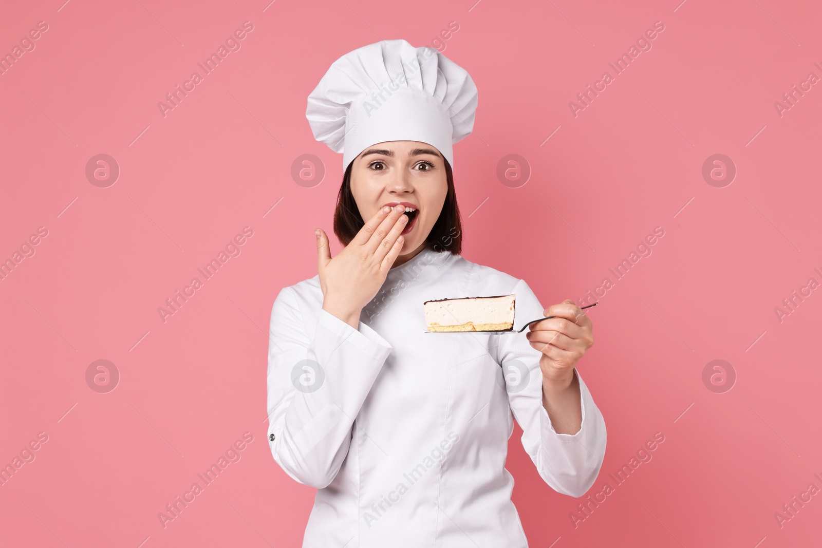 Photo of Happy confectioner with delicious cheesecake on pink background