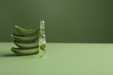 Photo of Skincare ampoules with extract of aloe vera and cut green leaves on color background. Space for text