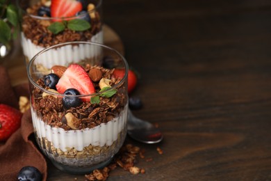 Photo of Tasty granola with berries, nuts, yogurt and chia seeds on wooden table, space for text