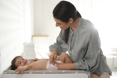 Photo of Mother changing baby's diaper on table at home