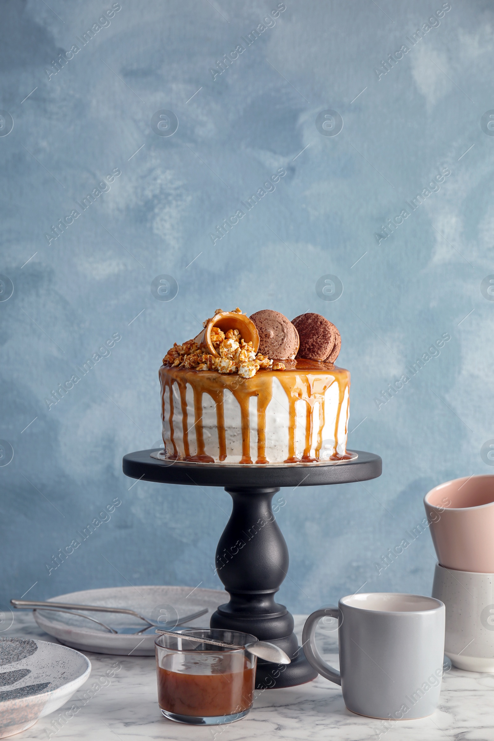 Photo of Dessert stand with delicious caramel cake on table against color background