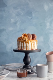 Photo of Dessert stand with delicious caramel cake on table against color background