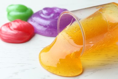 Different bright slimes on white wooden background, closeup