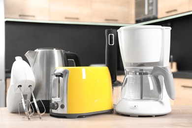 Modern domestic appliances on wooden table in kitchen