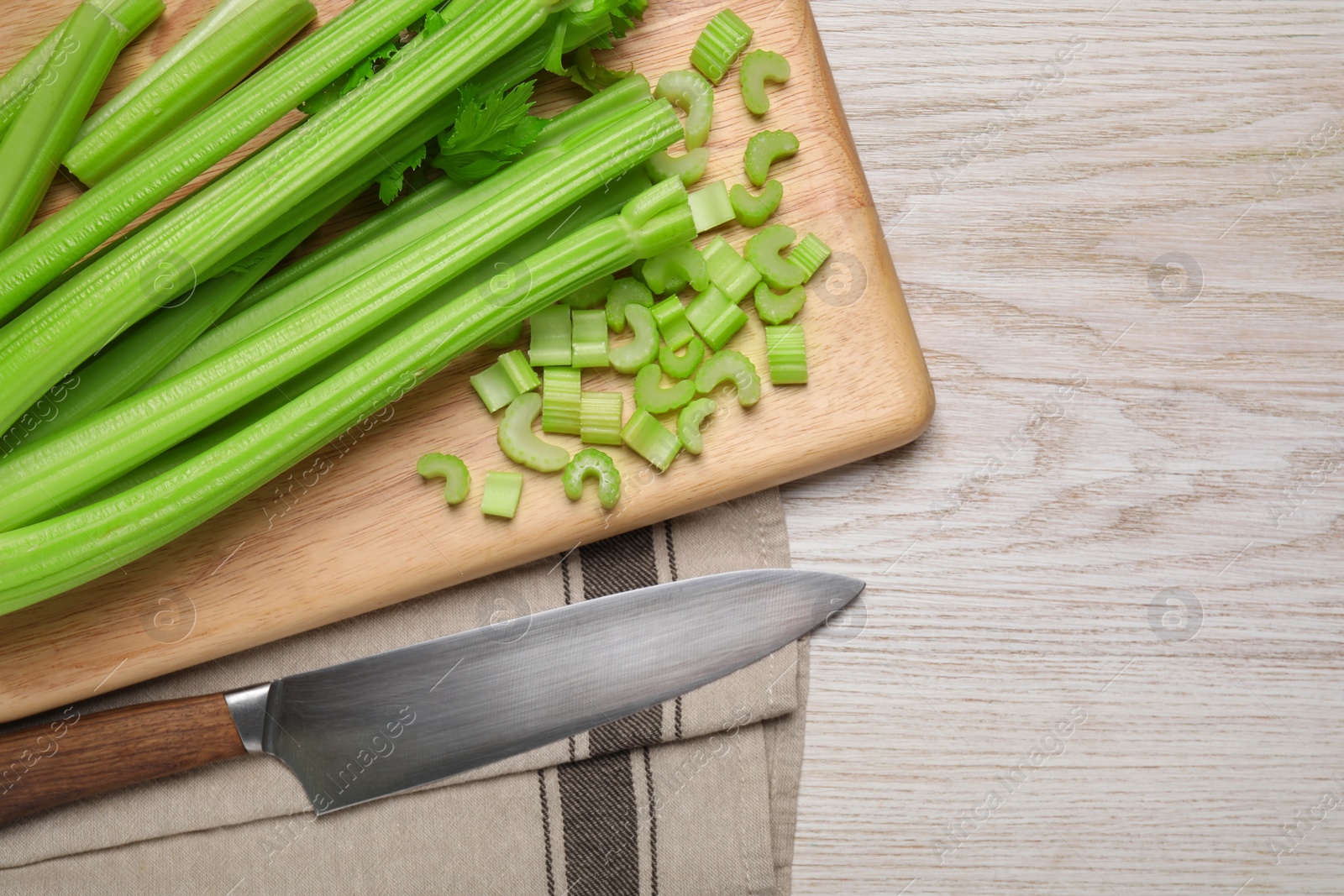 Photo of Fresh ripe celery and knife on white wooden table, flat lay. Space for text
