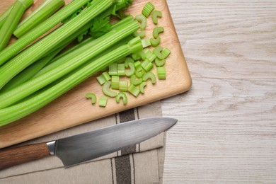 Photo of Fresh ripe celery and knife on white wooden table, flat lay. Space for text