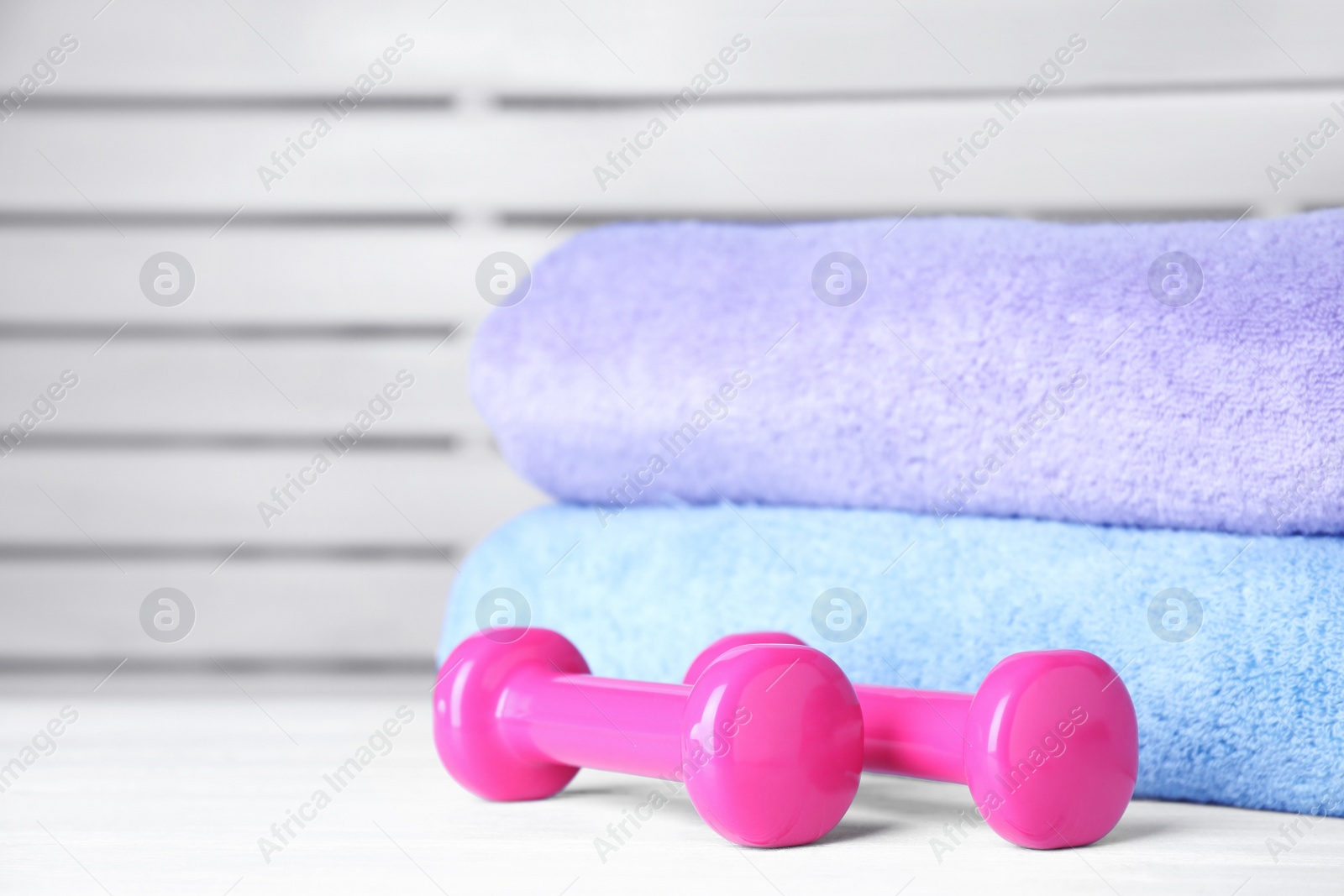 Photo of Vinyl dumbbells and towels on table, space for text