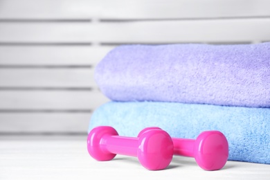 Photo of Vinyl dumbbells and towels on table, space for text