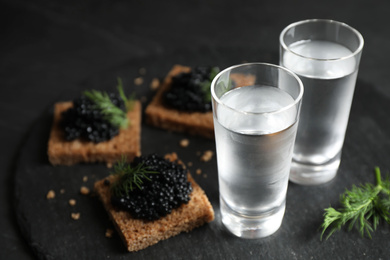 Photo of Cold Russian vodka and sandwiches with black caviar on table, closeup