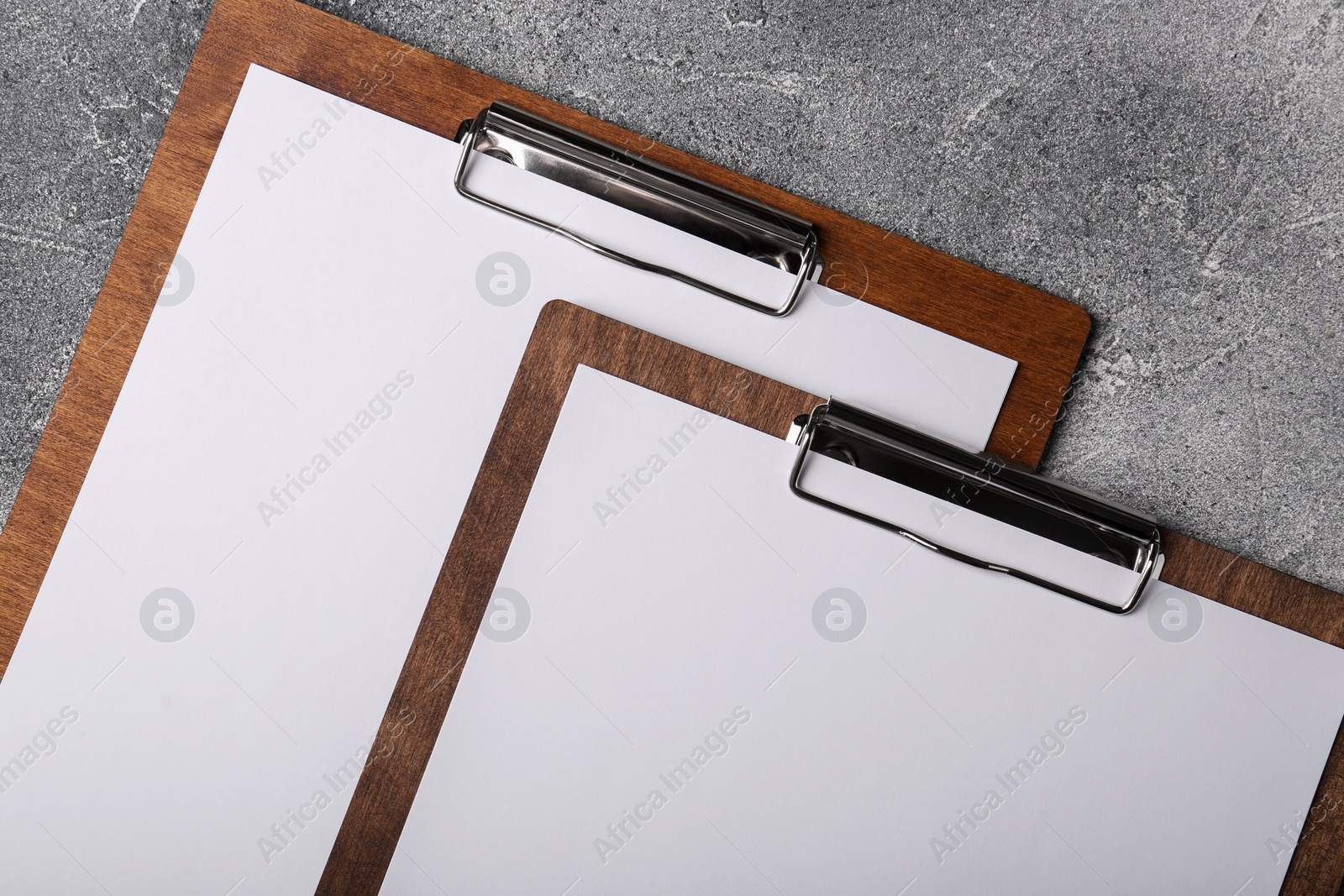 Photo of New wooden clipboards with sheets of blank paper on grey textured table, flat lay