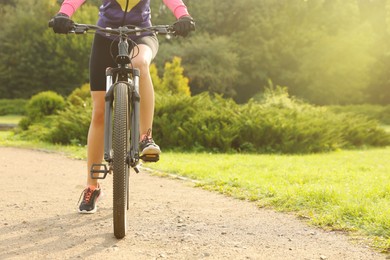 Young woman riding bicycle on road outdoors, closeup. Space for text