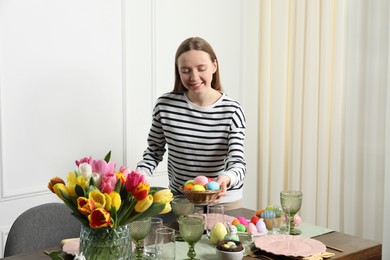 Photo of Woman setting table for festive Easter dinner at home