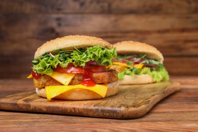 Photo of Delicious burgers with tofu, fresh vegetables and sauce on wooden table