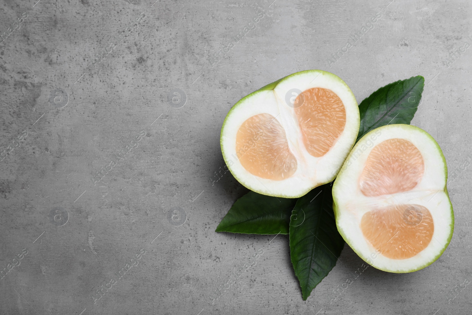 Photo of Cut sweetie fruit on grey table, flat lay. Space for text