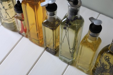 Bottles of different cooking oils on white wooden table, closeup