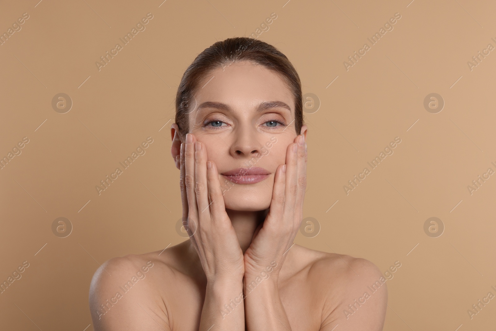 Photo of Woman massaging her face on beige background