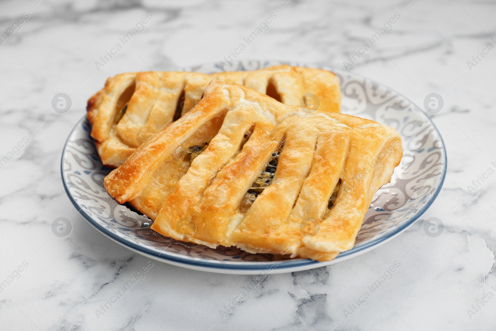 Photo of Fresh tasty puff pastry on white marble table, closeup