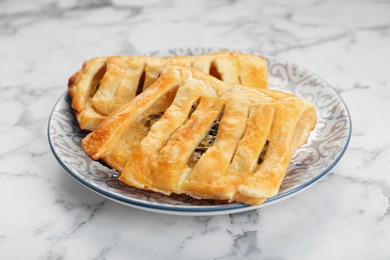 Photo of Fresh tasty puff pastry on white marble table, closeup