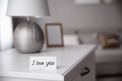 Photo of Paper with text I Love You on nightstand indoors