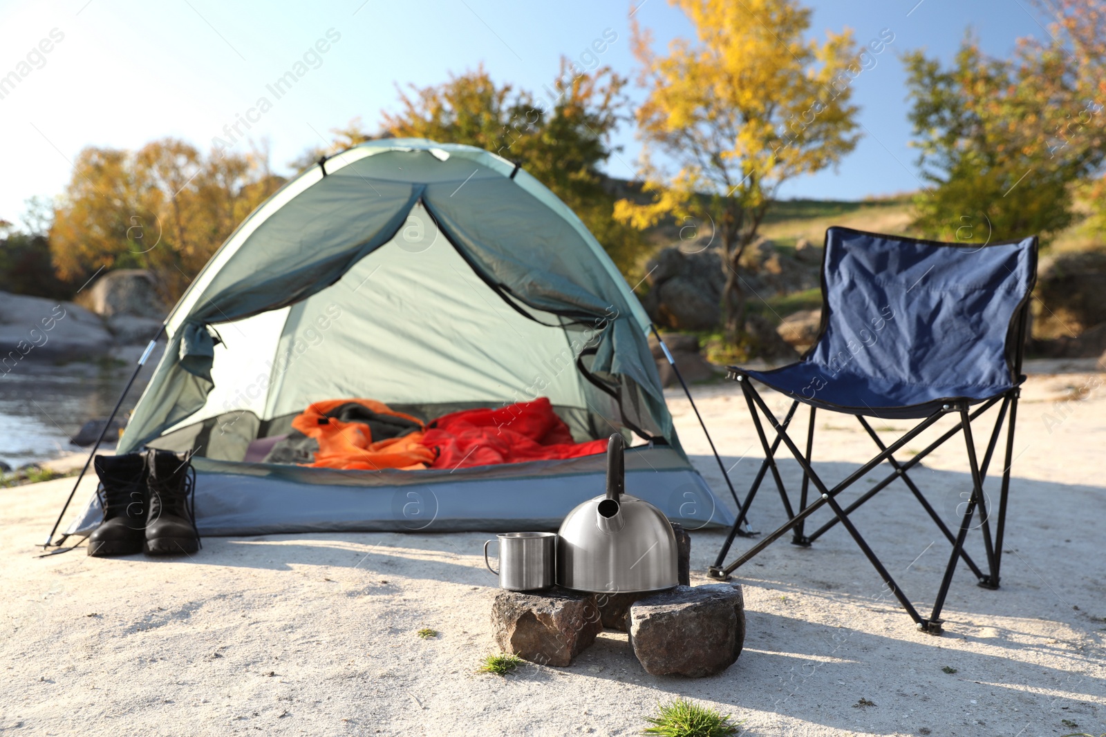 Photo of Camping equipment near tent with sleeping bag outdoors