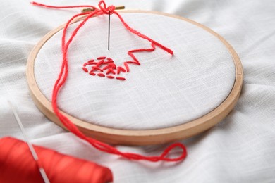 Photo of Sewing needle with thread and stitches on light cloth, closeup