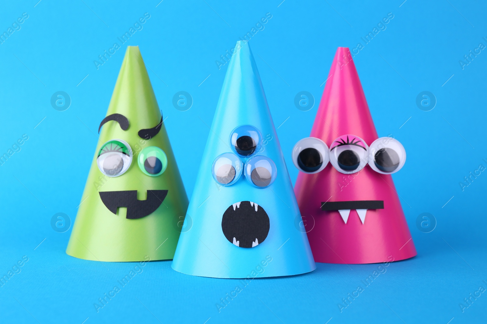 Photo of Spooky paper monsters on light blue background. Halloween decoration