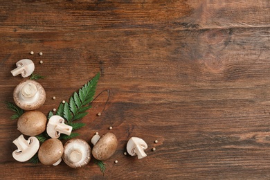 Frame made of fresh champignon mushrooms on wooden background, flat lay with space for text