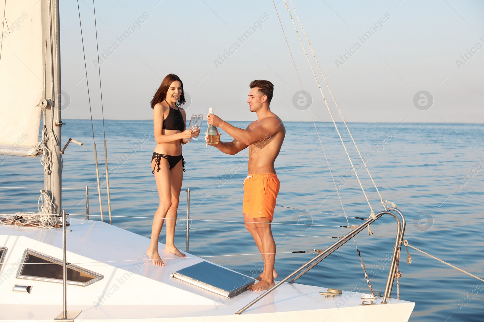 Photo of Young man and his girlfriend in bikini drinking champagne on yacht