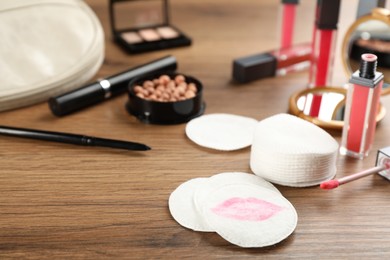 Photo of Dirty cotton pads and cosmetic products on wooden table