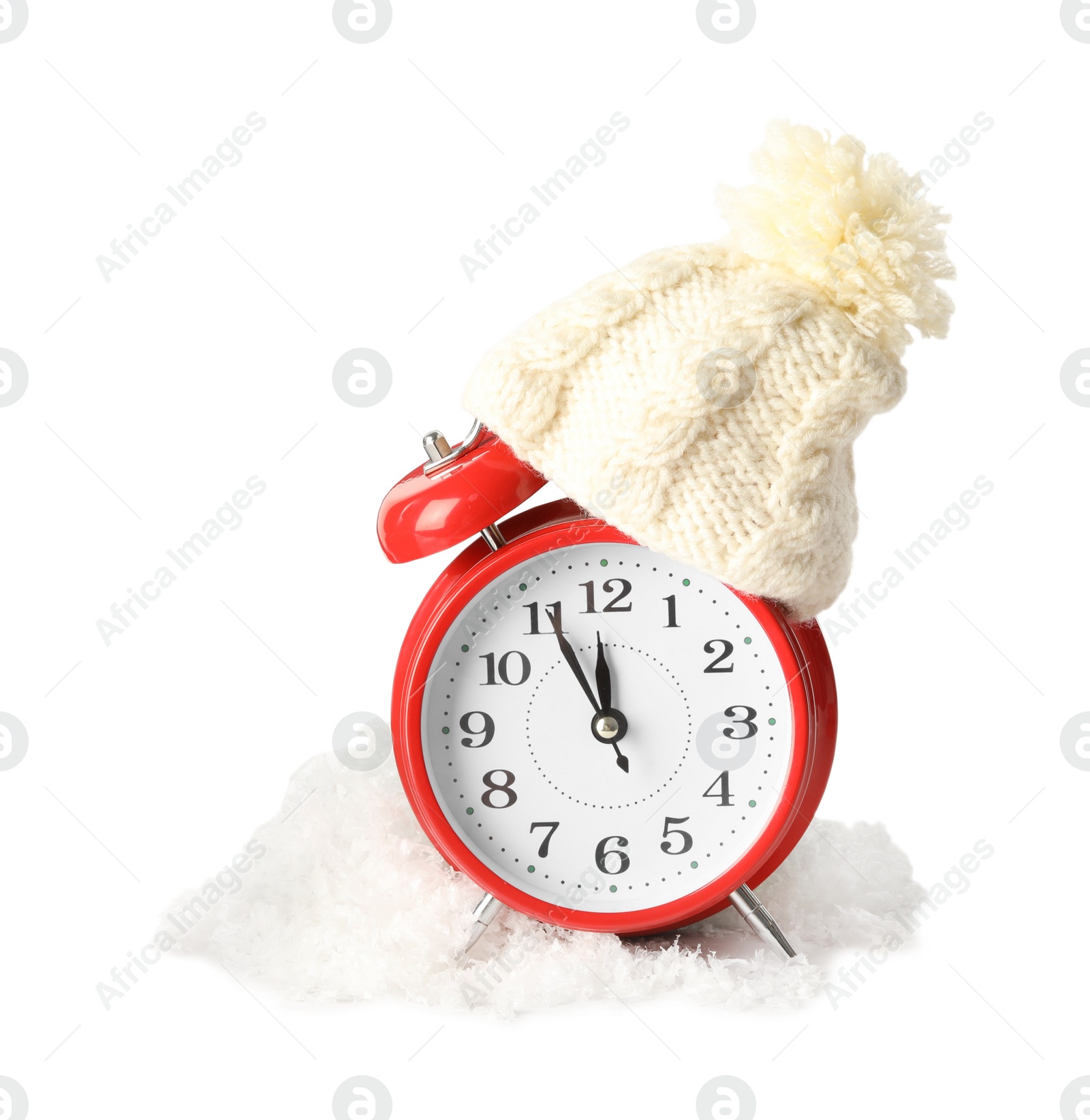 Photo of Alarm clock with hat in pile of snow on white background. New Year countdown