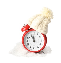 Photo of Alarm clock with hat in pile of snow on white background. New Year countdown