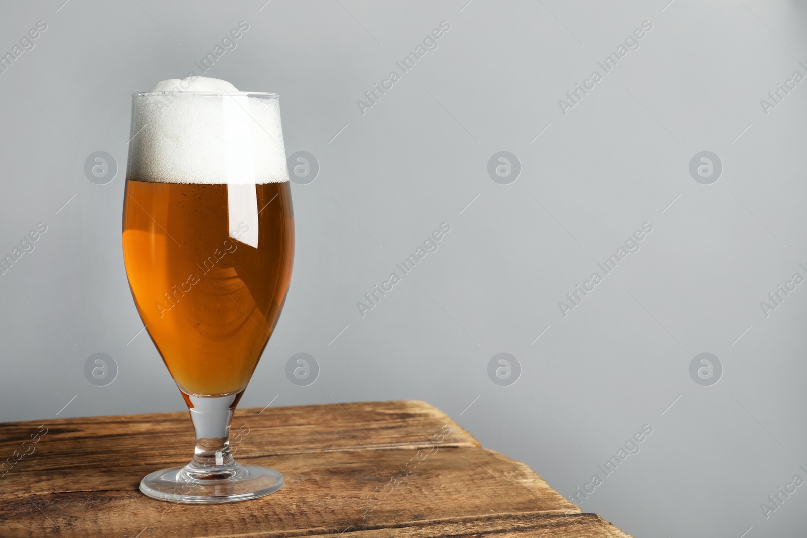 Photo of Glass of tasty beer on wooden table. Space for text