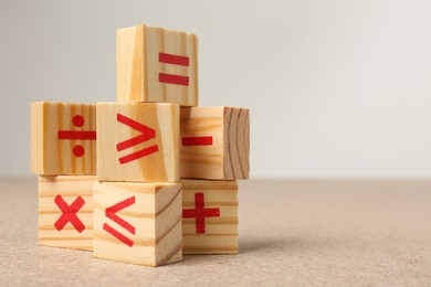 Wooden cubes with mathematical symbols on table against light background. Space for text